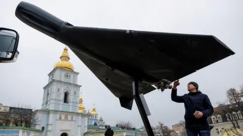 Reuters A man examines a Russian-Iranian Shahed drone displayed on a plinth outside St Michael's cathedral in central Kyiv