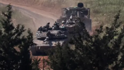 Reuters Tanks and an armoured vehicle drive in Lebanon, as seen from the Israeli side of the Israel-Lebanon border, in northern Israel