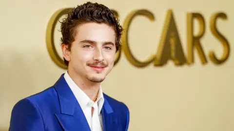 EPA Timothee Chalamet in a bright blue suit and white shirt, posing in front of the word Oscars on a wall in large gold letters, at the 98th Oscars Nominees Luncheon at the Beverly Hilton Hotel on 10 February 2026