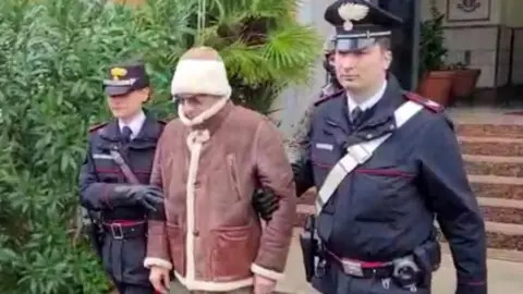 Reuters A screengrab taken from a video shows Matteo Messina Denaro the country's most wanted mafia boss being escorted out of a Carabinieri police station after he was arrested in Palermo, Italy, January 16, 2023.