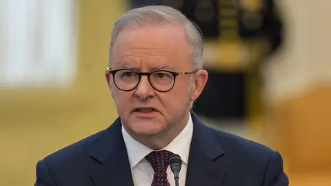 Getty Images Anthony Albanese wearing a navy suit and red and navy tie