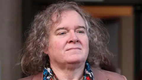 Reuters A middle aged woman with long curly grey hair wearing a colourful scarf