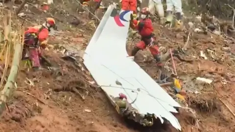 Getty Images Rescue teams with a piece of the fuselage of China Eastern passenger jet 