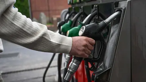 Anadolu via Getty Images A man grabs a black fuel pump at a petrol station