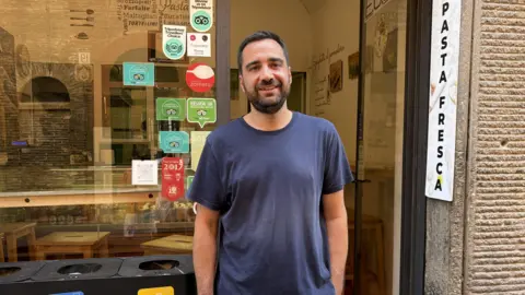 a man stands in front of a pasta shop