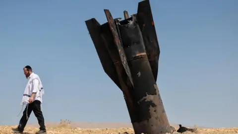 EPA An ultra-orthodox Jewish man walks away from the remains of an Iranian ballistic missile in an open field in th Jordan Valley