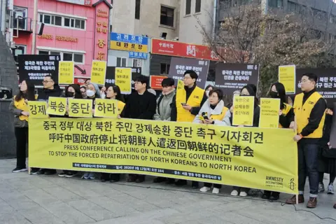 Handout A group of people wearing black and yellow, carrying placards and a big banner reading, in Korean and English: "Press conference calling on the Chinese government to stop the forced repatriation of North Koreans to North Korea"