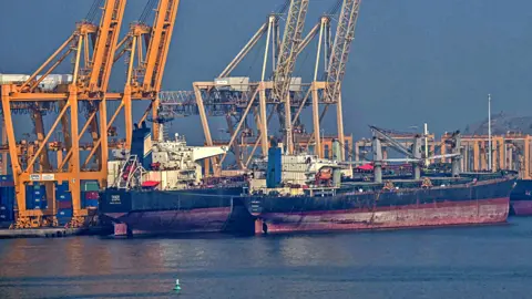 AFP via Getty Images Tankers are seen at the Khor Fakkan Container Terminal, the only natural deep-sea port in the region and one of the major container ports in the Sharjah Emirate, along the Strait of Hormuz, a waterway through which one-fifth of global oil output passes on June 23, 2025. 