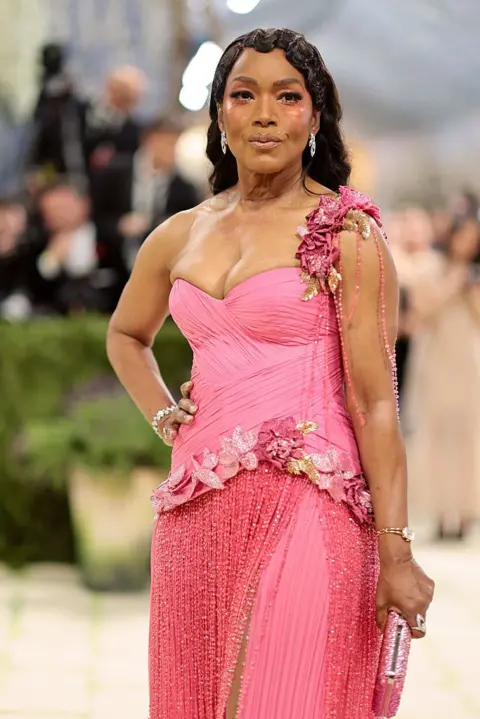 Getty Images Angela Bassett wears a pink gown with a single shoulder strap.