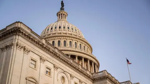 Getty Images Exterior photo of the US Capitol, a beige building with a circular dome atop. An American flag is flying in the corner.