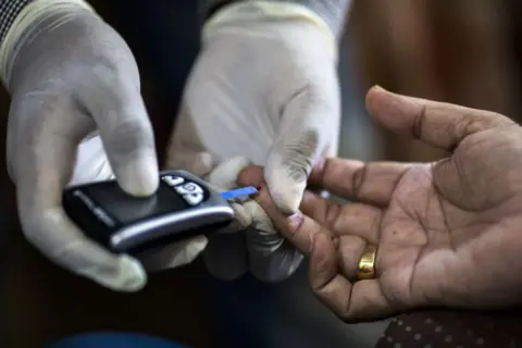 Prashanth Vishwanathan/Bloomberg via Getty Images A Public Health Foundation of India worker conducts a blood glucose test for a patient during a free door-to-door screening program funded by Eli Lilly & Co. at a home in the farming village of Thana kalan, Haryana, India, on Thursday, July 13, 2017. Global pharmaceutical companies, from Indianapolis-based Eli Lilly to Switzerlands Novartis AG, are heading into smaller cities and rural areas to learn about the health-care needs of about 70 percent of the population. These remote regions of the developing world are the final frontier for the international drug industry. Photographer: Prashanth Vishwanathan/Bloomberg via Getty Images