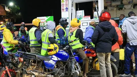 Anadolu via Getty Images Drivers and motorcycle taxi operators form long queues at a petrol station to purchase fuel