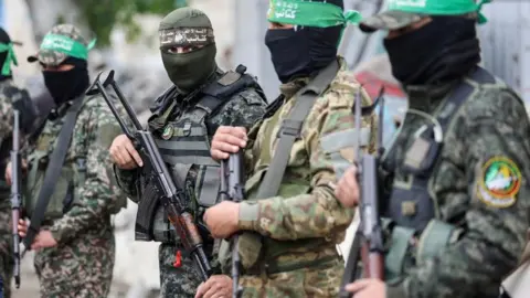Reuters Masked Palestinian gunmen in fatigues stand in a line in Gaza (07/02/26)