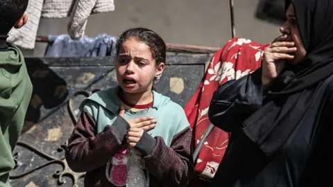 Anadolu via Getty Images A Palestinian girl cries during the funeral in Deir al-Balah for Majdi Aslan, a WHO contractor who was killed by Israeli forces in southern Gaza (6 April 2026)