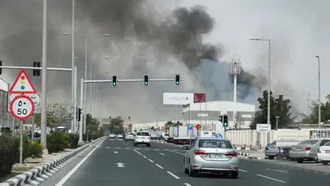 Reuters Smoke billows from the right side and rises over a large road of traffic in Qatar.