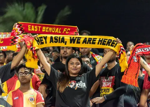 NurPhoto via Getty Images A young woman supporter of East Bengal FC cheers for her team before the commencement of the Indian Super League 2025-26 finale between East Bengal FC and Inter Kashi FC at the Kishore Bharati Stadium in Kolkata, India, on May 21, 2026. (Photo by Amlan Biswas/NurPhoto via Getty Images)