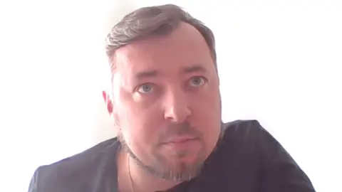 TG Premia Vorotnikova A blue-eyed man with greying hair and dark T-shirt.