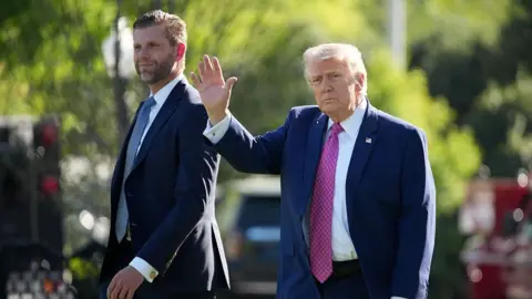 Getty Images Donald Trump waves as he walks alongside his son Eric. 