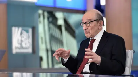 Getty Images Alan Greenspan giving an interview in 2018. He is sitting on the set of a television programme and is explaining a point to an unseen interviewer