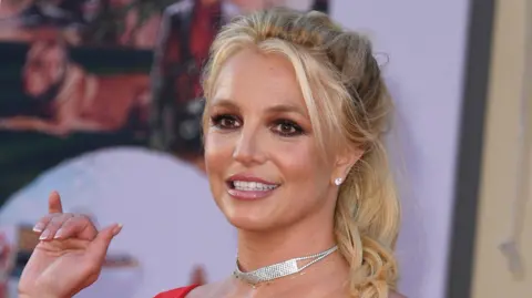 Getty Images Britney Spears in 2019 waving and smiling on the red carpet at a film premiere