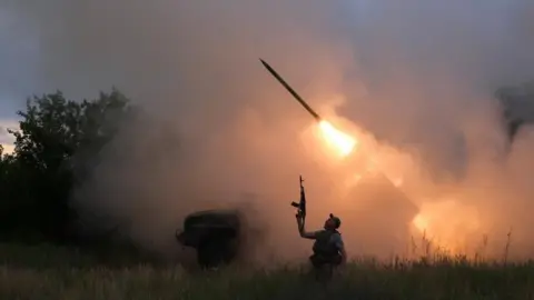 Reuters A Ukrainian soldier from the 93rd Kholodnyi Yar Separate Mechanized Brigade of the Ukrainian Armed Forces reacts as his colleagues fire a BM-21 Grad multiple launch rocket system towards Russian troops