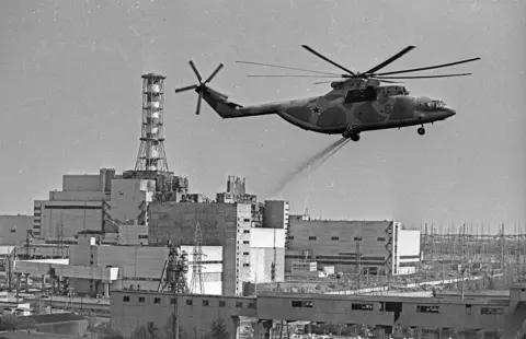 PhotoXpress/ZUMA Press/Shutterstock A black and white archive photo showing a helicopter spreads decontamination components over the contaminated area of Chernobyl Nuclear Power Plant.