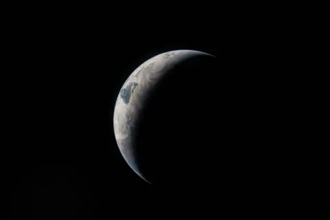 NASA A cresent view of the Earth with sunlight falling on th eright side of its surface in the blackness of space.