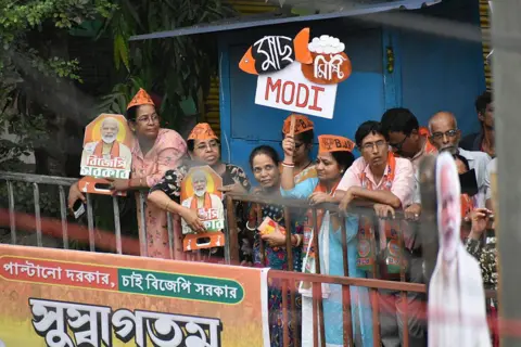 NurPhoto via Getty Images BJP supporters stand beside the road during a road show of Narendra Modi ahead of the second phase assembly election in Kolkata, India