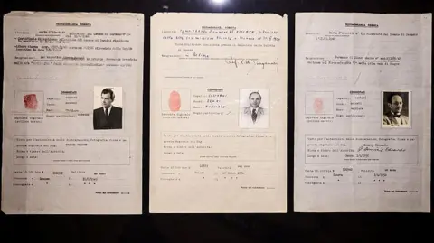 AFP via Getty Images Three documents with black and white photos showing passports
