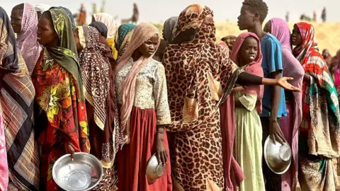 AFP via Getty Images People who fled the Zamzam camp for the internally displaced after it fell under RSF control, queue for food rations in a makeshift encampment in an open field near the town of Tawila in war-torn Sudan's western Darfur region on April.