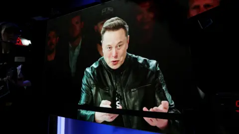 Reuters Elon Musk addresses supporters wearing a leather jacket speaking into a microphone ahead of SpaceX's launch on the Nasdaq stock exchange. 
