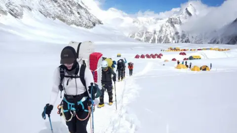 Reuters Members of an expedition team trudging through snow from Camp 1 to Camp 2 during a rotation trip. Dozens of tents are set up in the background.
