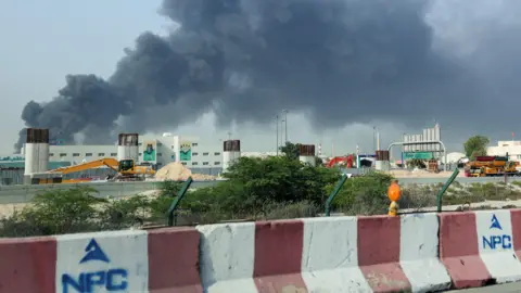 Reuters People run across a road with black smoke in the background. 