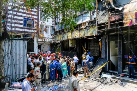 Reuters Firefighters and police officers stand at the site after a fire at a hotel in New Delhi