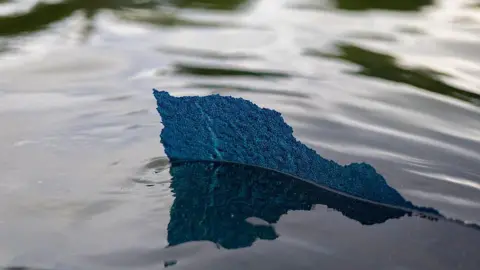 The Washington Post via Getty Images A piece of the new blue paint with a ragged edge, is seen above the water