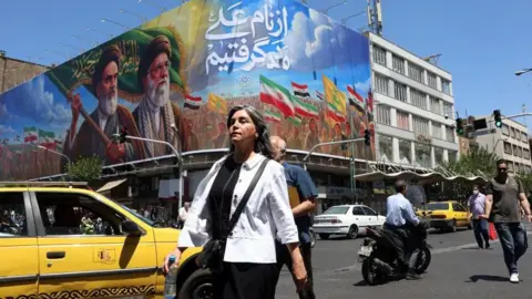 EPA Iranians walk past a billboard of the late Iranian supreme leaders, 15 June