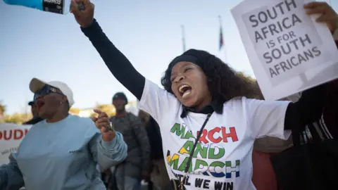 AFP via Getty Images A woman punches the air, while holding a placard reading