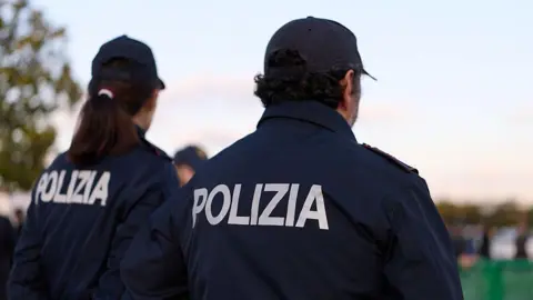 Getty Images File photo: A woman and a man in Italian police uniform standing with their backs to the camera