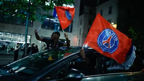AFP via Getty Images Paris Saint-Germain (PSG) supporters celebrate their team's progression to the Final of the UEFA Champions League near the Champs-Elysees after their second-leg semi-final football match against Bayern Munich, in Paris, on May 6, 2026
