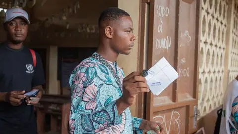 AFP via Getty Images Voters at a polling station in Benin on 11 January to cast ballots in the parliamentary election