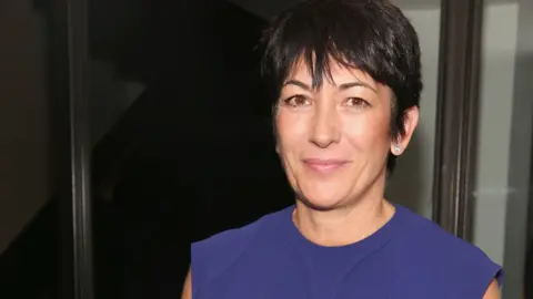 Getty Images Ghislaine Maxwell smiles while wearing a blue dress
