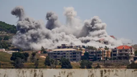 Reuters View from afar of large plumes of smoke rising over buildings struck by Israel in the Nabatieh area, southern Lebanon.