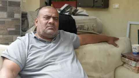 Fayez Awad sits on a sofa in his home Jerusalem's Old City.
