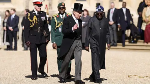 Reuters King Charles III with the President of Nigeria Bola Ahmed Tinubu on the Royal Dais during a welcome ceremony at Datchet Road in Windsor. Both men are dressed in black, with King Charles in a three-piece suit