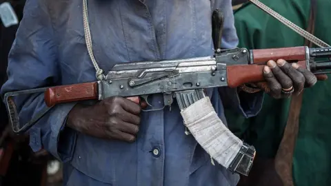 AFP via Getty Images An anonymous man holds a rifle.