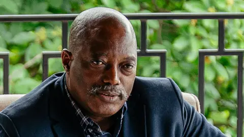 AFP via Getty Images A head and shoulders image of Joseph Kabila. He is wearing a blue jacket and open-necked blue chequered shirt.