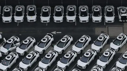Getty Images An overhead view of a fleet of white Waymo vehicles 