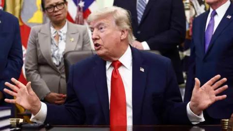Getty Images US President Donald Trump speaking in the Oval Office surrounded by people listening