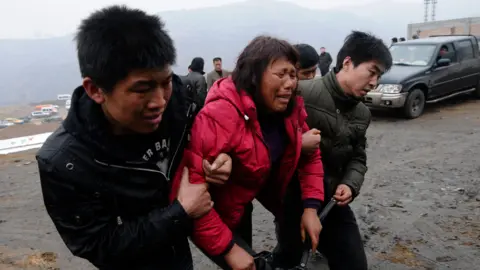 Getty Images Relatives of trapped coal mine workers are taken away from the site of a flooding accident at a mine in Shanxi province on March 29, 2010. 
