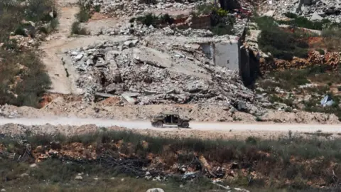 EPA An Israeli military vehicle drives along a road on the Lebanese side of the border with Israel, as seen from northern Israel (15 June 2026)